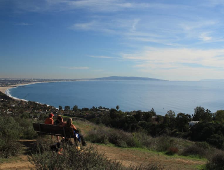 Los Leones Trail - A panoramic view from a high vantage point overlooking rolling hills, urban sprawl, and the Pacific Ocean